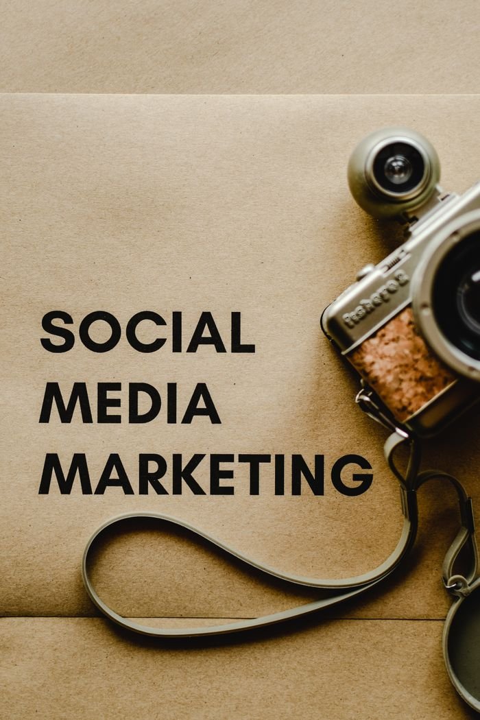 Home Close-up of a vintage camera next to a social media marketing concept text on a brown background.